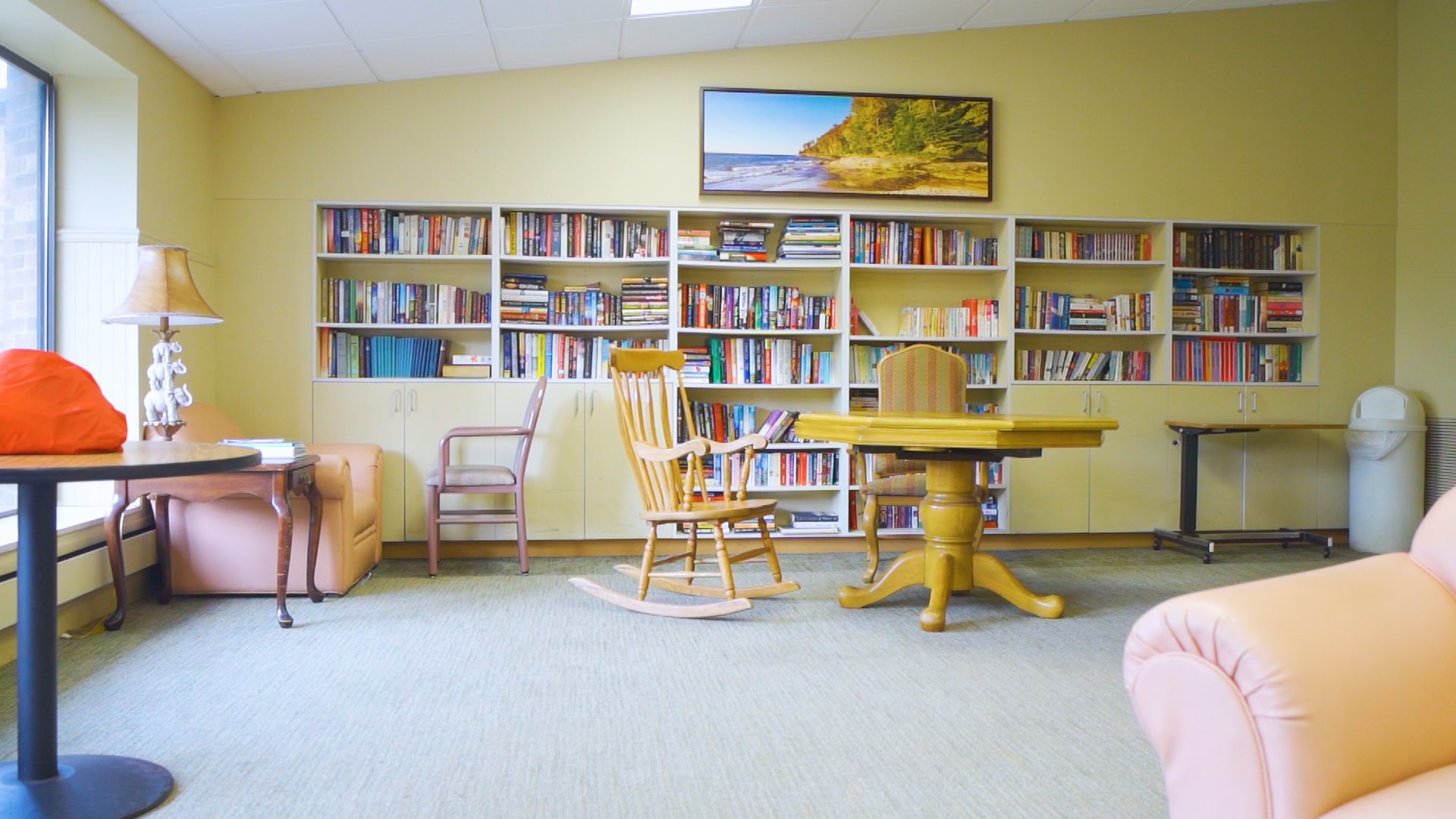 Bookshelf and table with chairs inside activity room.