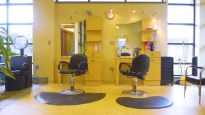 Two salon chair and mirrors inside salon.